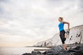 Young sporty woman runner with earphones stretching on the beach outside. Royalty Free Stock Photo