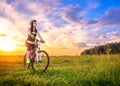 Young sporty woman at sunset on a bicycle. Sporty girl on bike stopped to enjoy the moment at beautiful sunset. Lens Royalty Free Stock Photo