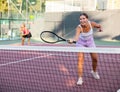 Young sporty woman tennis player dressed white t-shirt and shorts hitting ball with racket