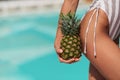 Young sporty woman in trendy sexy turquoise bodysuit hold pineapple near her perfect butt.