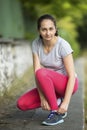 Young sporty woman tying running shoe laces before Jogging in park in sunshine on beautiful summer day. Royalty Free Stock Photo