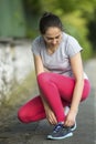 Young sporty woman tying running shoe laces in park in beautiful summer day Royalty Free Stock Photo