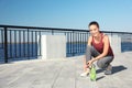 Young sporty woman tying shoelaces near bottle Royalty Free Stock Photo