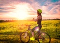 Young sporty woman watching the sunset on a bicycle. Sporty girl on bike stopped to enjoy the moment at beautiful sunset Royalty Free Stock Photo