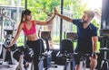 Young sporty woman and man giving each other a high five after cycling training in gym. Fit couple high five after workout Royalty Free Stock Photo