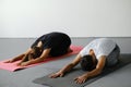 Young spotty girl and sporty man practice yoga, doing kid pose - Balasana. Training in a club, yoga studio.