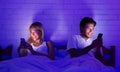 Young Spouses Using Phones Lying In Bed At Night