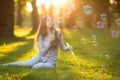 Young spring fashion casual woman blow bubbles in the sunset in