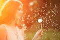 Young spring fashion woman blowing dandelion in spring garden. S