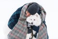 Young sri lankan man embracing solid white fluffy dog in winter. Royalty Free Stock Photo