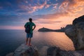 Young standing man with backpack on the stone at sunset Royalty Free Stock Photo