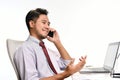 Young business man smiling while talking on the phone and working with laptop computer Royalty Free Stock Photo