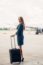 Young stewardess with suitcase on aircraft parking