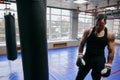 Young stong man standing near the punching bag , having a break after boxing