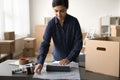 Young storage employee wrapping small black box for cardboard package Royalty Free Stock Photo