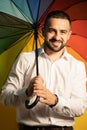 Young straight man with a rainbow umbrella behind his back. Healthy fashion lifestyle, people sincere emotions, cold