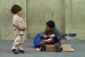 Young street musician boy playing his blue guitar while girl listening and enjoying