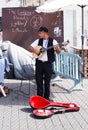 Young street musician playing the lute on the waterfront Royalty Free Stock Photo