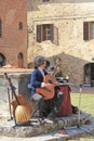 Young street musician playing on the square of the ancient city of San Gimignano