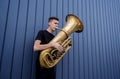 Young street musician playing the tuba near the big blue wall Royalty Free Stock Photo