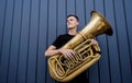 Young street musician playing the tuba near the big blue wall Royalty Free Stock Photo