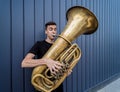 Young street musician playing the tuba near the big blue wall Royalty Free Stock Photo