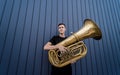 Young street musician playing the tuba near the big blue wall Royalty Free Stock Photo