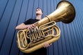 Young street musician playing the tuba near the big blue wall Royalty Free Stock Photo