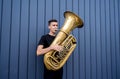 Young street musician playing the tuba near the big blue wall Royalty Free Stock Photo