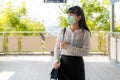 Young stress Asian businesswoman in white shirt going to work in pollution city she wears protection mask prevent PM2.5 dust, smog