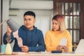 Young stressed asian couple managing finances, reviewing their bank accounts using laptop computer and calculator at modern home. Royalty Free Stock Photo