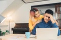 Young stressed asian couple managing finances, reviewing their bank accounts using laptop computer and calculator at modern home. Royalty Free Stock Photo