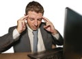 Young stressed businessman in suit and tie working overwhelmed at office laptop computer desk suffering headache cause of work Royalty Free Stock Photo