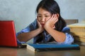 Young stressed and frustrated Asian Korean student girl working hard with laptop computer and books pile on desk overwhelmed and Royalty Free Stock Photo