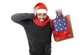 Young stressed man wearing santa hat holding red shopping bags Royalty Free Stock Photo