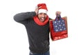 Young stressed man wearing santa hat holding red shopping bags Royalty Free Stock Photo