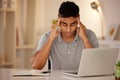 Young stressed man working alone on a laptop in an office at night. Guy looking tired and worried while struggling with Royalty Free Stock Photo