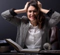 Young stressed student girl studying pile of books on library desk preparing test or exam in stress feeling Royalty Free Stock Photo