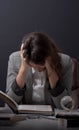 Young stressed student girl studying pile of books on library desk preparing test or exam in stress feeling Royalty Free Stock Photo