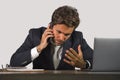 young stressed and upset business man working at office computer desk talking frustrated on mobile phone feeling tired Royalty Free Stock Photo