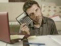 Young stressed and worried man at home living room using calculator and laptop doing domestic accounting paperwork feeling Royalty Free Stock Photo