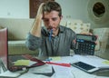 Young stressed and worried man at home living room using calculator and laptop doing domestic accounting paperwork feeling Royalty Free Stock Photo