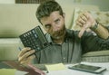 Young stressed and worried man at home living room using calculator and laptop doing domestic accounting paperwork feeling Royalty Free Stock Photo