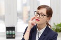 strict business woman in a blue jacket and glasses is thinking at the window in the office at her workplace Royalty Free Stock Photo