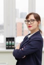 strict business woman in a blue jacket and glasses is thinking at the window in the office at her workplace Royalty Free Stock Photo