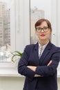 Strict business woman in a blue jacket and glasses is thinking at the window in the office at her workplace Royalty Free Stock Photo