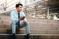 Young Striving Asian Businessman Sitting on Staircase in the City. Using Mobile Phone