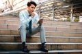 Young Striving Asian Businessman Using Mobile Phone in the City. Sitting on Staircase. Reading Seriously topic Royalty Free Stock Photo