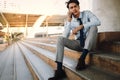 Young Striving Asian Businessman Using Mobile Phone in the City. Sitting on Staircase. Talking Seriously topic Royalty Free Stock Photo