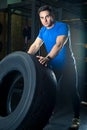 Young strong athlete posing with a heavy wheel